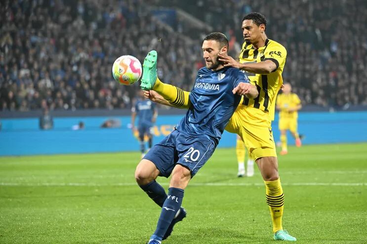 Sebastien Haller, delantero marfileño del Dortmund, intenta puntear el balón ante la marca de Ivan Ordets, defensor ucraniano del Bochum, durante el partido que empataron ayer.