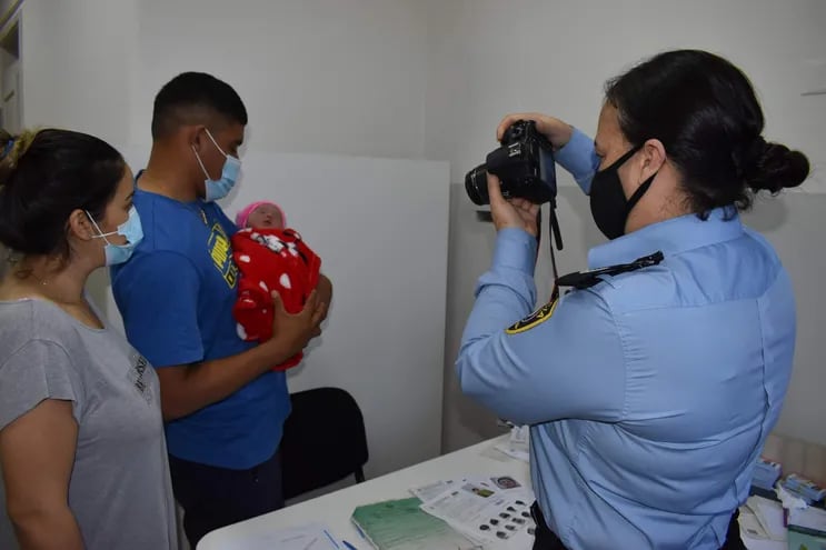 Momento en que la suboficial Nidia Ayala toma una fotografía a una recién nacida, en brazos de su padre Daniel Chávez y con la madre Sonia Amarilla observando.