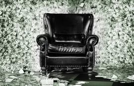 Un sillón de cuero negro rodeado de billetes de dólares.