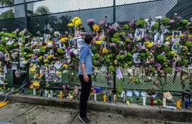 Leo Soutoagrega flores a un memorial con fotografías de los desaparecidos.