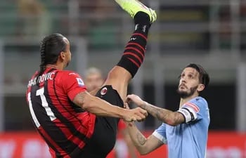 El suelo Zlatan Ibrahimovic, del AC Milan, extiende su pierna cuan largo es ante la presencia del español Luis Alberto, del Lazio, en un partido de la Serie A de Italia.