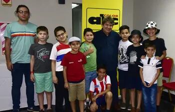 Zenón Franco con los niños y jóvenes con los que quienes se enfrentó al mismo tiempo en una entretenida sesión de simultáneas en ABC Color. Abajo, con camiseta albirroja, Diego Benítez (10 años), el único con el que firmó tablas.