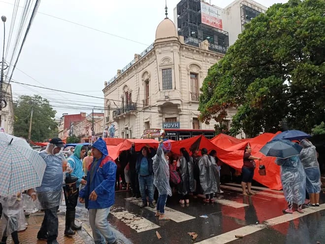 Miembros de la multisectorial se manifiestan frente el Ministerio de Urbanismo bajo la lluvia.