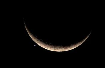 La luna en estado creciente junto a Venus en una imagen capturada en Bangkok. Astrónomos anuncian que esta semana se producirá un fenómeno planetario. (AFP)