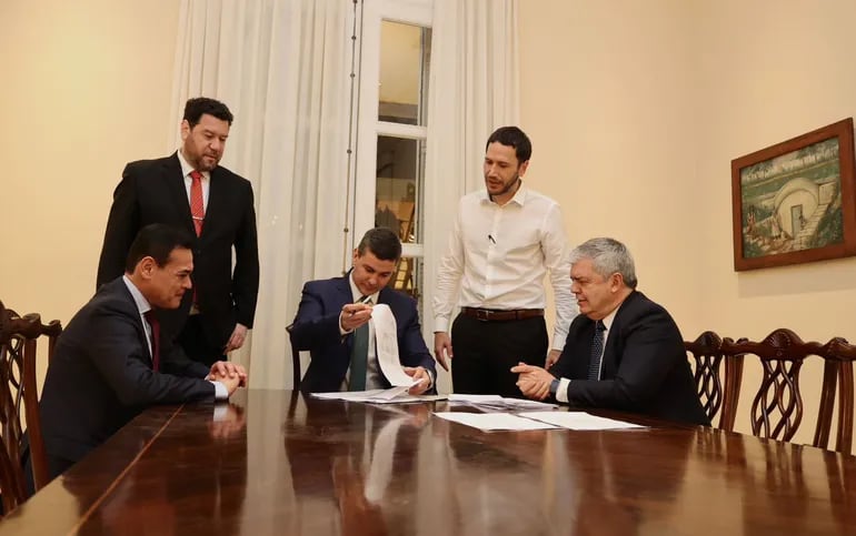 Santiago Peña, Presidente de la República (centro de la foto), firmando decretos ante la presencia de varias autoridades. (gentileza).