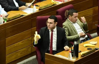 El senador cartista Hernán Rivas come una banana mientras se vota su desafuero. A su lado, su colega Javier "Chaqueñito" Vera se distrae con el celular.