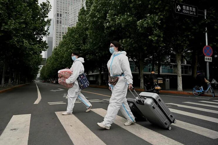 Personas visten equipos de protección personal en una calle de Pekín, China.  (AFP)