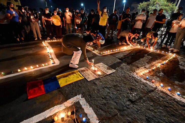 People place lit candles on the ground during a vigil on May 5, 2021 in Cali, Colombia, in honor of the demonstrators who died during protests against the government of President Ivan Duque. - Thousands of people returned to the streets of Colombia on May 5 in rejection of the government of Ivan Duque, who has completed a week of pressure with demonstrations that turned violent in some cities and left some twenty people dead. (Photo by Luis ROBAYO / AFP)