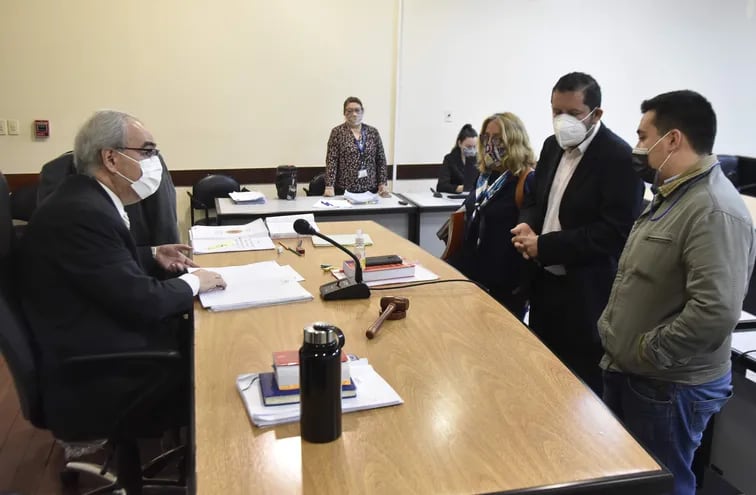 El acusado Stiben Patrón (de campera verde) charla con el presidente del Tribunal de Sentencia, Héctor Escobar, tras declarar en el juicio oral por la quema del Congreso.