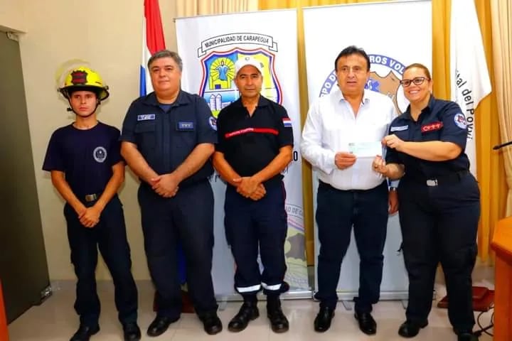 El intendente Luciano Cañete (ANR), hace entrega del cheque por un monto de G.5 millones a la presidenta de los bomberos Marta Miranda.