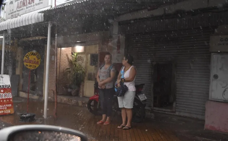 Dos mujeres se resguardan de la lluvia en Asunción.