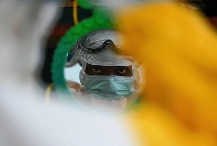 Un trabajador de Médicos Sin Fronteras con traje de protección se mira en un espejo en Kailahun, Guinea, en agosto de 2014.