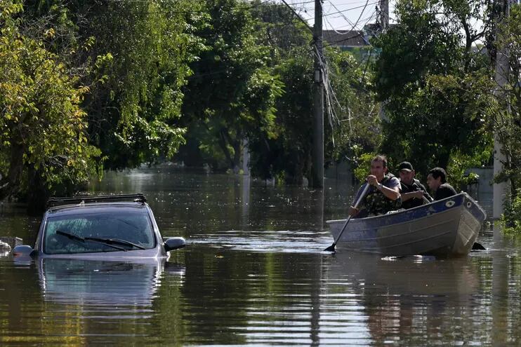 Vecinos de Porto Alegre, Brasil, son trasladados en canoa por una zona inundada de la ciudad, este lunes.