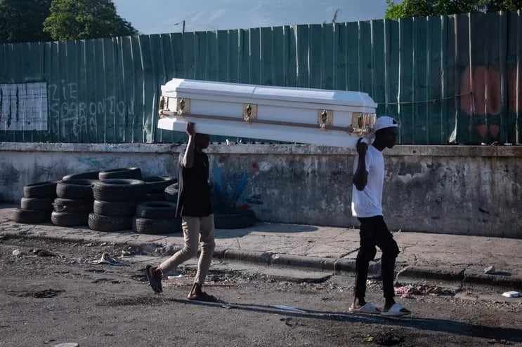 Dos hombres cargan un ataúd por una calleen Puerto Príncipe (Haití). Presuntos delincuentes fueron abatidos por la Policía Nacional de Haití durante un ataque al Palacio Nacional el fin de semana en Puerto Príncipe, orquestado por la coalición de bandas armadas "Vivre Ensemble", según publicaron este sábado medios locales. EFE/ Johnson Sabin
