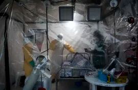 En esta foto de archivo tomada el 15 de agosto de 2018, tres trabajadores médicos controlan a un paciente con ébola en un Biosecure Emergency Care Unite (CUBE).