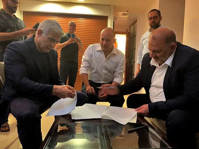 Mansur Abás (a la derecha), líder del partido árabe israelí Raam, firma un acuerdo de coalición con el líder opositor israelí Yair Lapid (a la izquierda) y el ultraderechista Naftalí Benet.