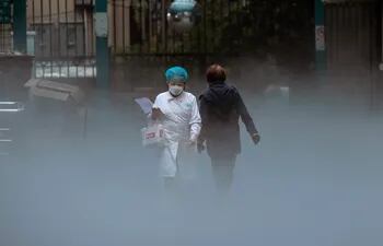 Un personal médico sale de la parte mortuoria de un hospital mientras otra persona acaba de entrar en las instalaciones en Shanghái, China . (EFE)