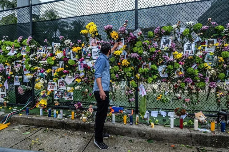 Leo Soutoagrega flores a un memorial con fotografías de los desaparecidos.