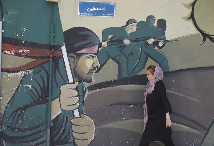 Una mujer iraní camina junto a una pintura mural de soldados del cuerpo de guardia revolucionario iraní (IRGC) en Teherán, Irán, este domingo. El Cuerpo de Guardias Revolucionarios Islámicos de Irán (IRGC) lanzó drones y cohetes hacia Israel a última hora del 13 de abril de 2024, dijeron funcionarios iraníes.