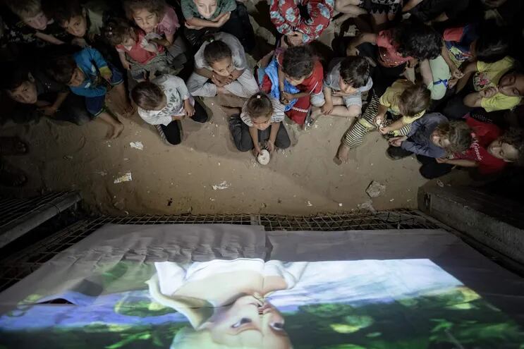 Niños ven una película en un cine improvisado entre las tiendas del campo de refugiados de Rafah, en el sur de Gaza.