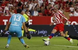 El delantero del Atlético de Madrid Antoine Griezmann (d) dispara a puerta ante Yassine Bounou, portero del Sevilla FC, durante el partido de la jornada 7 de LaLiga que se juega hoy sábado en el estadio Sánchez-Pizjuán, en Sevilla.