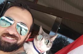 Jhon Galvis y la gata Bella, conocida como el Gato mochilero, en una foto que publicaron el 14 de agosto para celebrar el Día de la Bandera paraguaya.