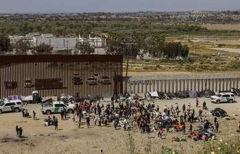 Fotografía general donde se observa a migrantes en un campamento junto al muro fronterizo, el 9 de mayo de 2023, en Tijuana, Baja California (México).