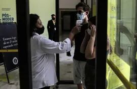 Una mujer toma la temperatura a visitantes del Centro Cultural Banco do Brasil, en Río de Janeiro (Brasil).  Los casos y muertes por covid van en descenso.
