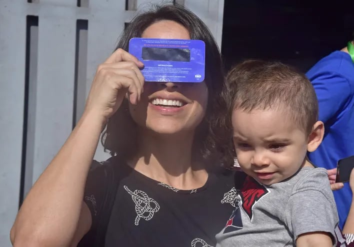 Una madre observa un eclipse solar con su hijo en brazos.