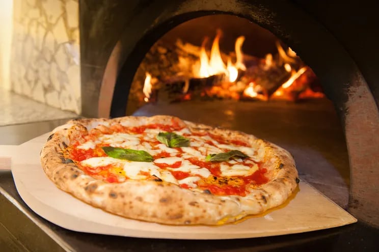 Una pizza napolitana es retirada de un horno con una pala.