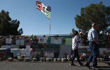 Dos personas caminan frente al memorial instalado a las afueras del centro comercial Walmart de El Paso, donde tuvo lugar el tiroteo.