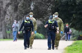 Oficiales de policía y soldados patrullan una popular pista de atletismo en Melbourne, el 4 de agosto de 2020, después de que el estado anunciara nuevas restricciones a medida que la ciudad lucha contra nuevos brotes del coronavirus COVID-19.
