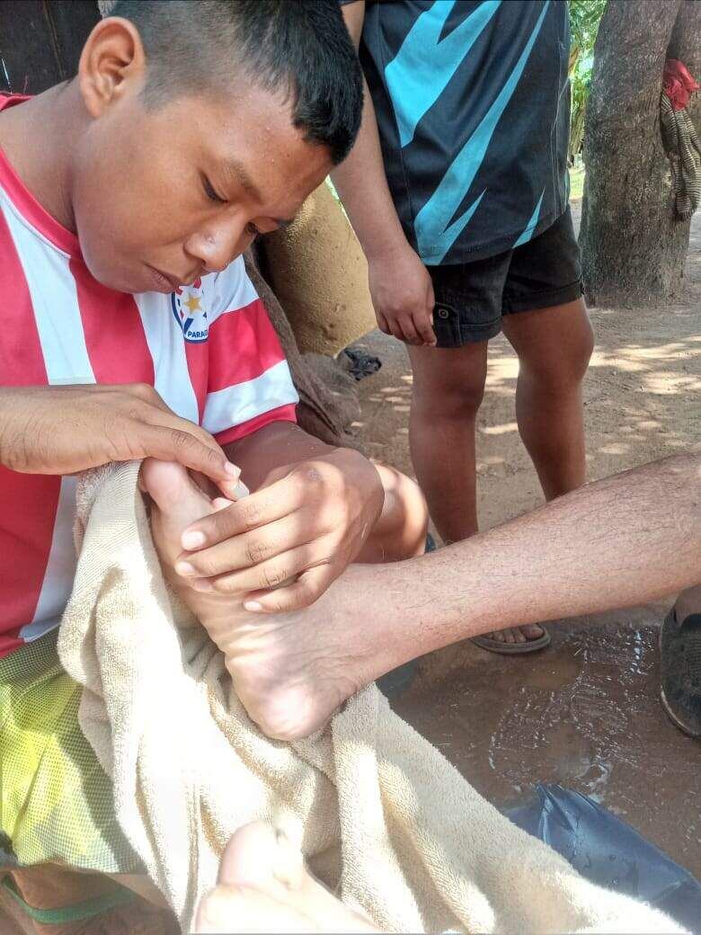 Un joven, con aprecio único, realiza su tarea de limpiar el pie del abuelo. 