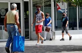 Varias personas usan tapabocas mientras caminan por una calle, en La Habana, Cuba, que aumentó hoy la censura en redes.  (EFE)