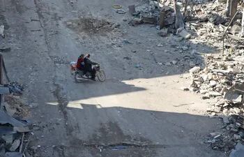 Dos personas recorren en motocicleta una zona dañada por bombardeos en la ciudad de Maaret Al-Numan, en la provincia siria de Idlib.