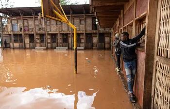 Dos personas unas un muro para cruzar una zona inundada en Nairobi, Kenia, el miércoles.
