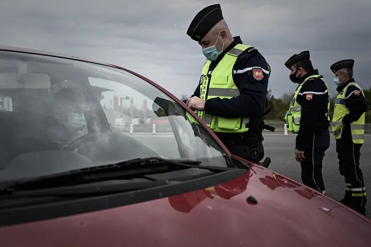 Un oficial de la gendarmería francesa controla a un conductor en una salida de la autopista A10 que une París y Burdeos, durante el cierre destinado a frenar la propagación de la pandemia Covid-19 en Virsac, suroeste de Francia, el 9 de abril de 2021.