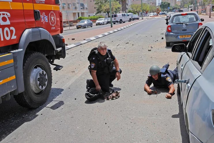 Miembros de las fuerzas de seguridad israelíes se tiran al suelo, mientras desde la franja de Gaza se lanzan cohetes, controlados por Hamas, en la ciudad de Ashkelon, Israel.