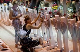 Dos mujeres visitan un memorial en homenaje a las víctimas del derrumbe del edificio Champlain Towers South en Surfside, Florida.