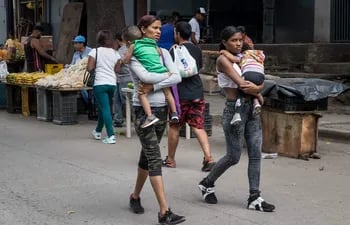 Mujeres caminan con unos niñosen Caracas (Venezuela).