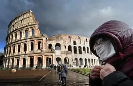Un visitante utiliza una mascarilla frente al Coliseo Romano.