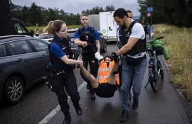 Agentes de Policía detienen a un activista de 'Renovate Switzerland' luego de que este y otros se pegaran al asfalto en una autopista, como medida de protesta.