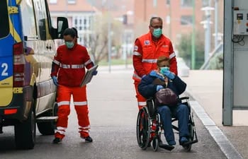 Un trabajador de la salud empuja a una mujer en una silla de ruedas frente al Hospital de Burgos (UBU), en el norte de España.