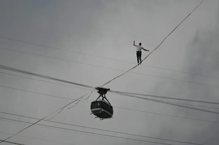 Highliner Nathan Paulin crosses balanced on a slackline next to the Sugar Loaf Cable Car at Praia Vermelha, beside Sugarloaf Mountain, in Rio de Janeiro, Brazil on December 4, 2021. - The performance is part of the Les Traceurs project conceived by French choreographer Rachid Ouramdane, current director of the Theater Chaillot, from Paris. (Photo by ANDRE BORGES / AFP)