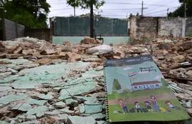 Un cuaderno del kit escolar reposa entre los escombros donde Engineering SA debe levantar una sala de clases, en la escuela Delfín Chamorro del barrio Roberto L. Petit.