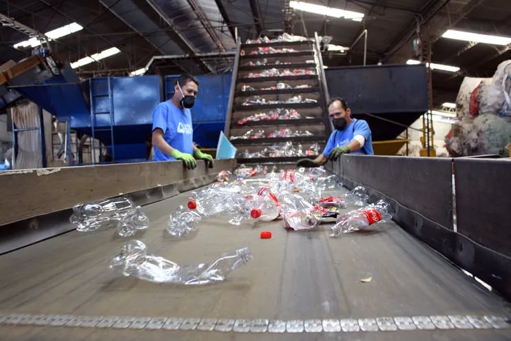 Dos personas reciclan una botellas de plástico en una fábrica en Honduras, en el marco del programa de recolección y reciclaje "Hagámosla Circular" de la Cervecería Hondureña, empresa subsidiaria de AB InBev.