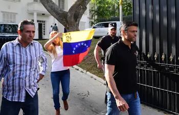 En esta foto de archivo tomada el 2 de mayo de 2019, el destacado político opositor venezolano Leopoldo López (derecha) seguido de su esposa Lilian Tintori (c) portando una bandera venezolana, sale de la embajada de España en Caracas.