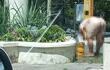Con la ayuda de un balde, un hombre totalmente desnudo busca aplacar el intenso calor en la fuente ubicada en 25 de mayo y México.