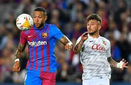 Memphis Depay, que marcó el primer gol para Barcelona, tiene en la mira el balón ante el acoso del defensor Pablo Maffeo, de Mallorca.