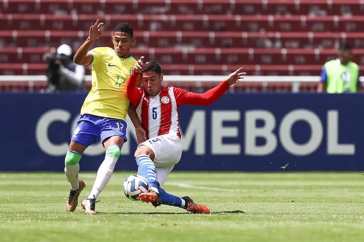 El defensor paraguayo Óscar López se arroja al suelo y le roba el balón con mucha precisión al brasileño Riquelme de Souza.